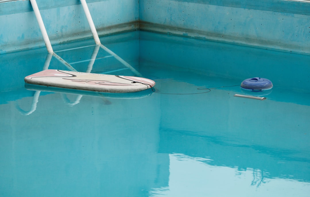 Weekly Pool Maintenance 1 Pool skimmer net removing debris from clear blue residential pool water during weekly maintenance